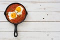 Mexican breakfast: Huevos rancheros in iron frying pan on white wooden table top view Royalty Free Stock Photo