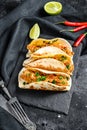 Mexican carnitas tacos with parsley, cheese and chili pepper. Black background. Top view