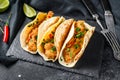 Mexican carnitas tacos with parsley, cheese and chili pepper. Black background. Top view