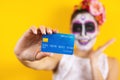 Mexican Catrina, portrait of young latin woman holding a credit card for Halloween party in Mexico Royalty Free Stock Photo