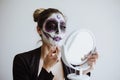 Mexican Catrina, young latin woman putting on makeup her self and making a traditional skeleton for Day of the Dead or Halloween Royalty Free Stock Photo