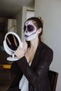 Mexican Catrina, young latin woman putting on makeup her self and making a traditional skeleton for Day of the Dead or Halloween Royalty Free Stock Photo