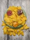 Mexican chips on a green plate with different sauces on gray rustic wooden background top view