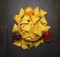 Mexican chips in a wooden bowl with cheese,ketchup, barbecue sauce on rustic wooden background close up top view Royalty Free Stock Photo