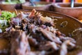 Mexican chopped lamb meat, hot sauces, and lime slices in clay bowls