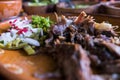 Mexican chopped lamb meat, hot sauces, and lime slices in clay bowls