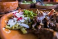 Mexican chopped lamb meat, hot sauces, and lime slices in clay bowls