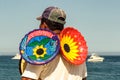 Mexican crafts vendor walks the beach showing colorful plates.