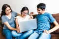 Mexican family and teenage daughter with down syndrome sitting on the sofa with computer at home, in disability concept in Latin