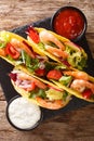 Mexican fast food tacos with shrimps, fresh vegetables and sauces close-up. Vertical top view Royalty Free Stock Photo