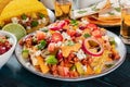 Mexican food. Nachos with beef, beans, chili peppers, onions and cheese sauce close-up, with pork tacos, quesadillas and tequila Royalty Free Stock Photo