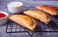Mexican fried meat pies empanadas cheburek on the baking rack with dips