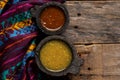 Mexican green and red sauce in molcajete on wooden background