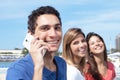 Mexican guy talking at phone with two girlfriends in the background Royalty Free Stock Photo