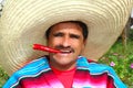 Mexican man poncho sombrero eating red hot chili Royalty Free Stock Photo