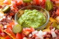 Mexican nachos with beef, guacamole, cheese sauce, peppers, tomato and onion