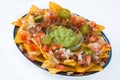 Mexican nachos with beef, guacamole, cheese sauce, peppers, tomato and onion in plate isolated Royalty Free Stock Photo