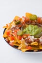 Mexican nachos with beef, guacamole, cheese sauce, peppers, tomato and onion in plate isolated Royalty Free Stock Photo