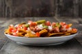 Mexican nachos with beef, guacamole, cheese sauce, peppers, tomato and onion in plate on wood