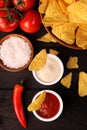 Mexican nachos in Wooden Bowl tortilla chips with chilli sauce, salsa and cheese dip, top view and Black Background Royalty Free Stock Photo