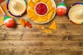 Mexican party background with nacho chips, maracas, pepper and sombrero hat. Cinco de Mayo holiday flat lay border. Top view Royalty Free Stock Photo