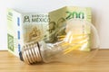 Mexican 200 pesos and a light bulb, Concept of rising energy and electricity prices in Mexico Royalty Free Stock Photo