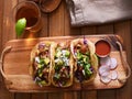 Mexican pork carnitas tacos with beer on wooden tray and radish garnish