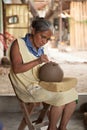 Mexican senior woman cutting designs into barro negro pottery, O