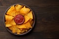 Mexican snack nachos or tortilla in clay plate with dip sauce on rustic wooden background.