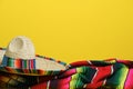 Mexican sombrero on a colorful serape blanket on a yellow background. Cinco de Mayo theme Royalty Free Stock Photo