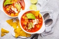 Mexican soup Chili con carne with beans, chicken, corn and nachos in white bowls - traditional mexican food