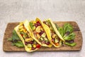 Mexican taco with chicken meat, red beans, fresh vegetables on wooden board. Latin american food, stone background