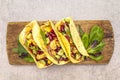 Mexican taco with chicken meat, red beans, fresh vegetables on wooden board. Latin american food, stone background