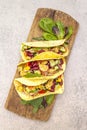 Mexican taco with chicken meat, red beans, fresh vegetables on wooden board. Latin american food, stone background, top view copy