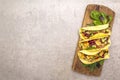 Mexican taco with chicken meat, red beans, fresh vegetables on wooden board. Latin american food, stone background, top view copy