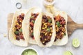 Mexican tacos with meat, beans, tomatoes, corn, paprika and cilantro on wooden board on shabby background