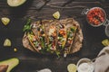 Mexican tacos with salsa and avocado on the wooden background, top view