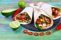 Mexican tacos - traditional dish with ingredients meat and vegetables on the plate on wooden background
