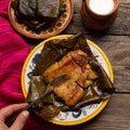 Mexican tamales in banana leaves on wooden background