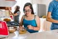 Mexican teenage girl with down syndrome with her family cooking in the kitchen at home, in disability concept in Latin America