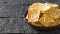 Mexican tortilla chips with cheese in a clay bowl on a black wooden table. Royalty Free Stock Photo