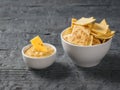 Mexican tortilla chips with cheese in a white bowl on a black wooden table. Royalty Free Stock Photo