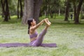 Mexican woman doing yoga exercises in the park on green grass