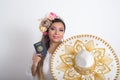 Mexican woman with flower headdress holding a mexican passport and mariachi hat. Woman with sombrero