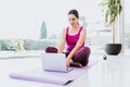 Mexican woman sitting on the floor watching yoga videos on laptop at home in Latin America Royalty Free Stock Photo