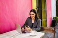 Mexican woman working with her computer on a coffee shop terrace in the streets of a colonial city in Latin America