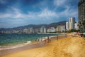 Mexico, Acapulca Beach - a sandy bay surrounded by tall hotels. On the beach sunbeds, umbrellas playing people in the ocean waters