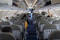 Rows of grey seats and empty aisle, open luggage cabinets and open door of Mexican airplane