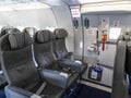 Inside of an empty commercial plane with grey leather seats next to emergency exit Royalty Free Stock Photo
