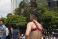 Man proudly wearing a red bondage type item on his chest watching the crowd of protesters in the march for LGBTTI pride